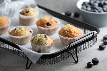 Delicious sweet muffins with blueberries on grey table