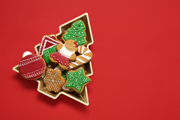 Fototapeta na wymiar Delicious cookies in Christmas tree-shaped bowl on red background