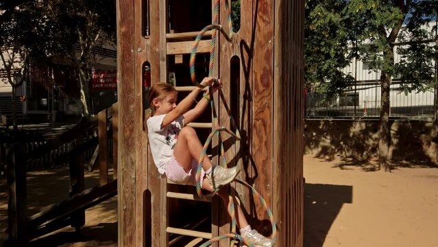 young girl climbing rope on wooden playground, Barcelona - Catalonia