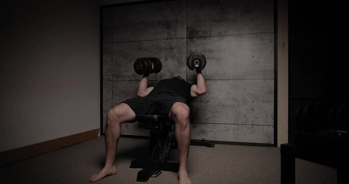 Incline dumbbell chest fly, cinematic lighting, white man dressed in black gym attire.