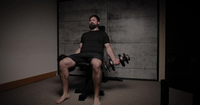 Seated incline dumbbell curls, cinematic lighting, white man dressed in black gym attire.