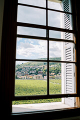 View from the window of a green lawn and ancient houses at the foot of the mountains