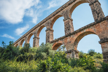 Fototapeta premium Pont del Diable: Majestuoso Acueducto de Tarragona Bajo un Cielo Azul Matutino