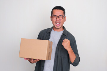 Adult Asian man showing excited expression while holding a box of package