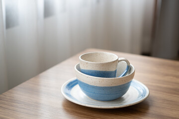 Stack of vintage blue tableware on wood table at window