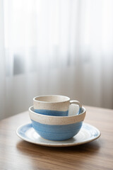Vertical sack of vintage blue tableware on wood table at window