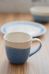 Close of vertical vintage cup with blue and white tableware on wood table