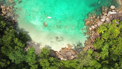 Drone of Anse major beach, bird eye shot of 4 tourist snorkelling near boat, granite stones, turquoise water and white sandy beach, Mahe Seychelles 30 fps