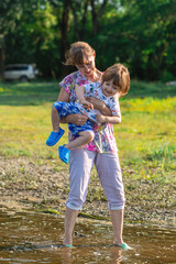 Fototapeta premium Grandson and grandmother playing on the river bank