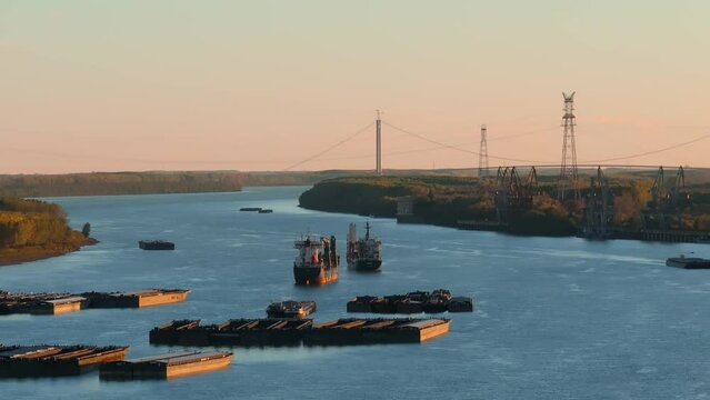Aerial rising close up shot of anchored ships on a big blue river,  suspended bridge in the brackground, clear sunny day, 4K50Fps