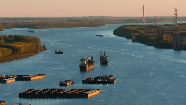 Aerial tracking close up shot of anchored ships on a big blue river,  suspended bridge in the brackground, clear sunny day, 4K50Fps