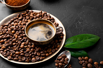 Obraz na płótnie Canvas Coffee background - cup of black coffee, coffee beans and ground coffee on a black background, copy space for text