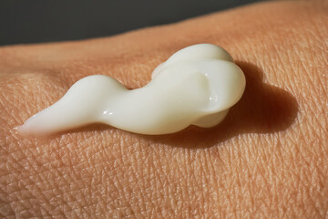 A smear of white moisturizer or sunscreen on a woman's hand.