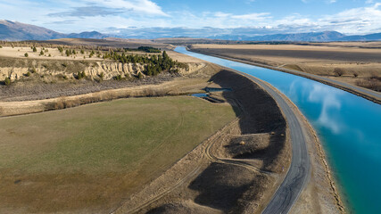 Aerial view of the Pukaki hydro power scheme canal in rural Twizel running in parallel with the now capped Ben Ohau mountain range