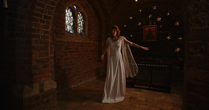 Woman in a beautiful long dress dancing in an old chapel