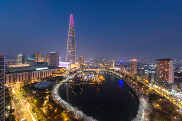 High angle and night view of of Seokchon Lake with cherry blossoms and Lotte World against Lotte...