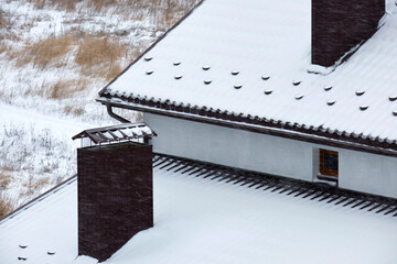 Snow guard for safety in winter on house roof top covered with ceramic shingles. Tiled covering of building - obrazy, fototapety, plakaty