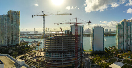 Tower lifting cranes at high residential apartment building construction site. Real estate development in Miami urban area
