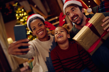 Happy multiracial family taking selfie on Christmas eve.