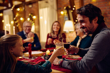 Happy father and daughter toasting during family meal at Christmas.