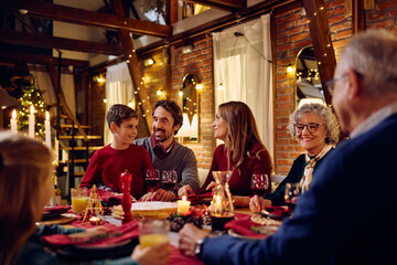 Happy extended family talks during Christmas dinner at dining table.