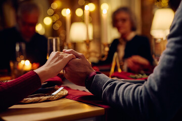 Close up of couple saying grace during family dinner on Christmas eve.