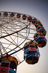 Closeup of multi-coloured Giant Wheel during Dussehra Mela in Delhi, India. Bottom view of Giant Wheel swing. Ferriswheel with colourful cabins during day time.