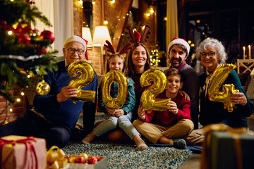 Happy extended family holds 2024 numbers while celebrating upcoming New Year.