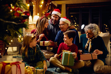 Happy extended family opening presents by Christmas tree at home. - obrazy, fototapety, plakaty