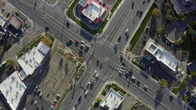 Rotating aerial drone bird's eye top view shot of a busy road intersection in the middle of a business center surrounded by buildings on a sunny fall day in Salt Lake county, Utah