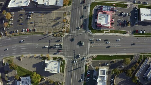 Aerial drone bird's eye top view shot of a busy road intersection in the middle of a business center surrounded by buildings on a sunny fall day in Salt Lake county, Utah