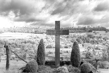Ein Kreuz mit einer schönen Landschaft im Hintergrund und in Schwarz/Weiß.