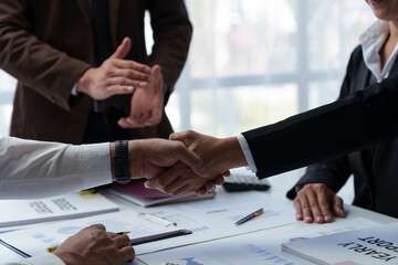 Businessmen shake hands to end the meeting. Successful negotiations and handshakes Group of business people congratulating each other inside the office.