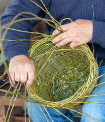 A man weaves a basket with willow branches