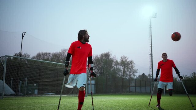 Legs of disabled football plaer with ball and crutches
