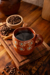 Cafe de Olla, Mexican-style coffee prepared with roasted and ground coffee beans, cinnamon and piloncillo. Traditional recipe prepared in a clay pot and served in a clay cup called a jarrito.
