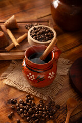 Cafe de Olla, Mexican-style coffee prepared with roasted and ground coffee beans, cinnamon and piloncillo. Traditional recipe prepared in a clay pot and served in a clay cup called a jarrito.