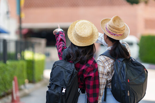 Travellers two young female tourists, Asian backpackers travel from place to place with cell phones to search for information on tourist attractions on a relaxing vacation. Lifestyle, Holiday concept