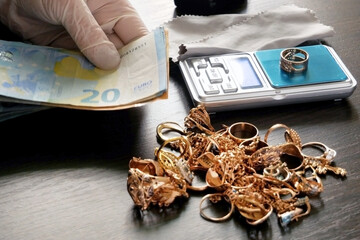 pawnshop worker counts money for gold jewelry on many golden and silver jewelleries background. Customers Buy and Sell Precious Metals, Jewels, Ancient Coins and Second Hand Appliances. Closeup - obrazy, fototapety, plakaty