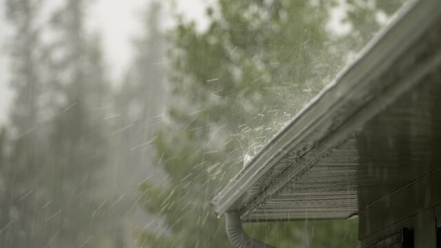 Hail and rain storm on rooftop of house with trees in background. close up
