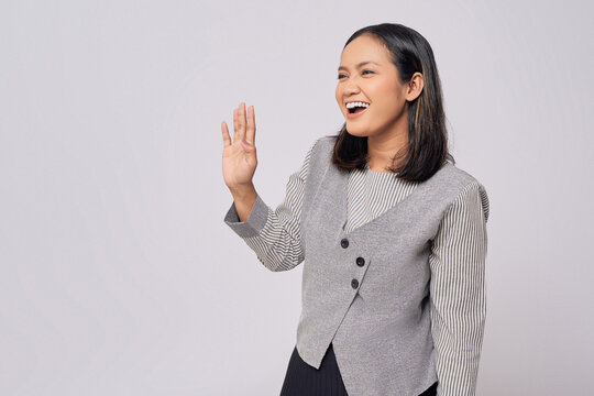 Smiling happy beautiful young Asian woman in casual clothes saying hello, showing hi gesture with waving hands with friendly expression isolated on white background. People lifestyle emotion concept