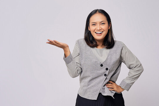 Smiling beautiful young Asian woman in casual clothes posing with both hands presenting something isolated on white background. People lifestyle concept