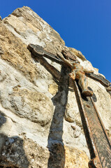 Christian iron cross against an ancient stone wall