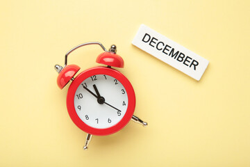 December 2024 Monthly calendar year with alarm clock on beige background.