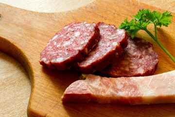 Sausage and bacon on a cutting board. Meat products on a wooden cutting board.