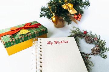 open notepad with christmas wish list text. decorated christmas tree on background
