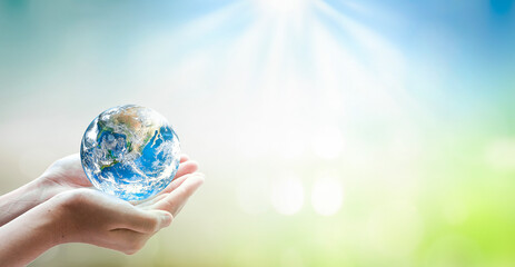 Earth day concept, Human hand holding globe on blurred green and blue nature background. Elements...