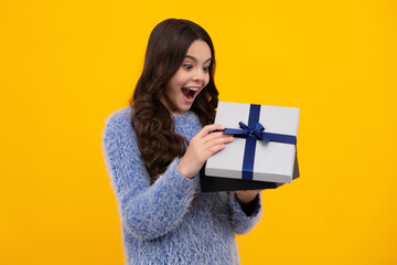 Amazed teenager. Funny kid girl in winter wear holding gift boxes celebrating happy New Year or...
