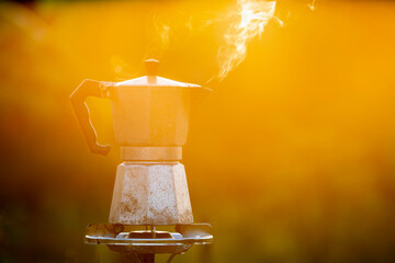 Moka pot and smoke, Steam from the coffee pot on fire, In the forest at sunrise in the morning. soft focus. shallow focus effect.