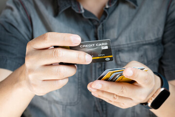 Man holding several credit cards and he is choosing a credit card to pay and spend Payment for goods via credit card. Finance and banking concept.	
